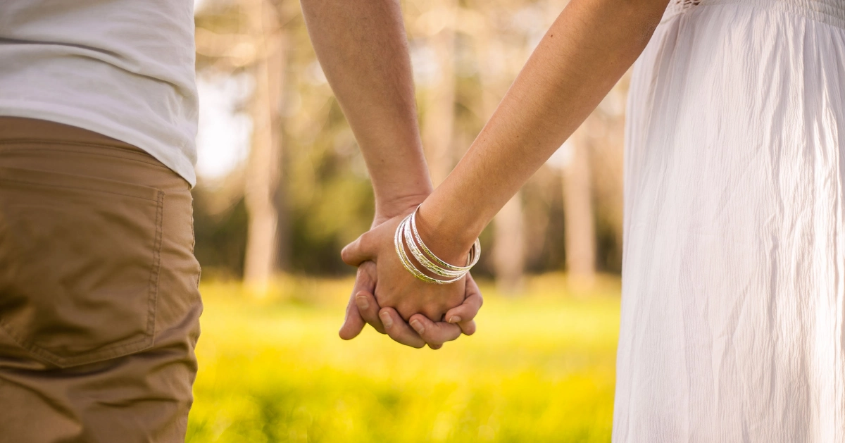 A couple holding hands outside.