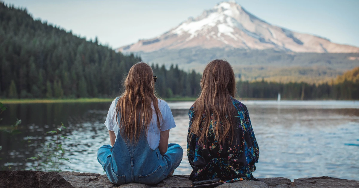 Two girls sitting on a rock wall.