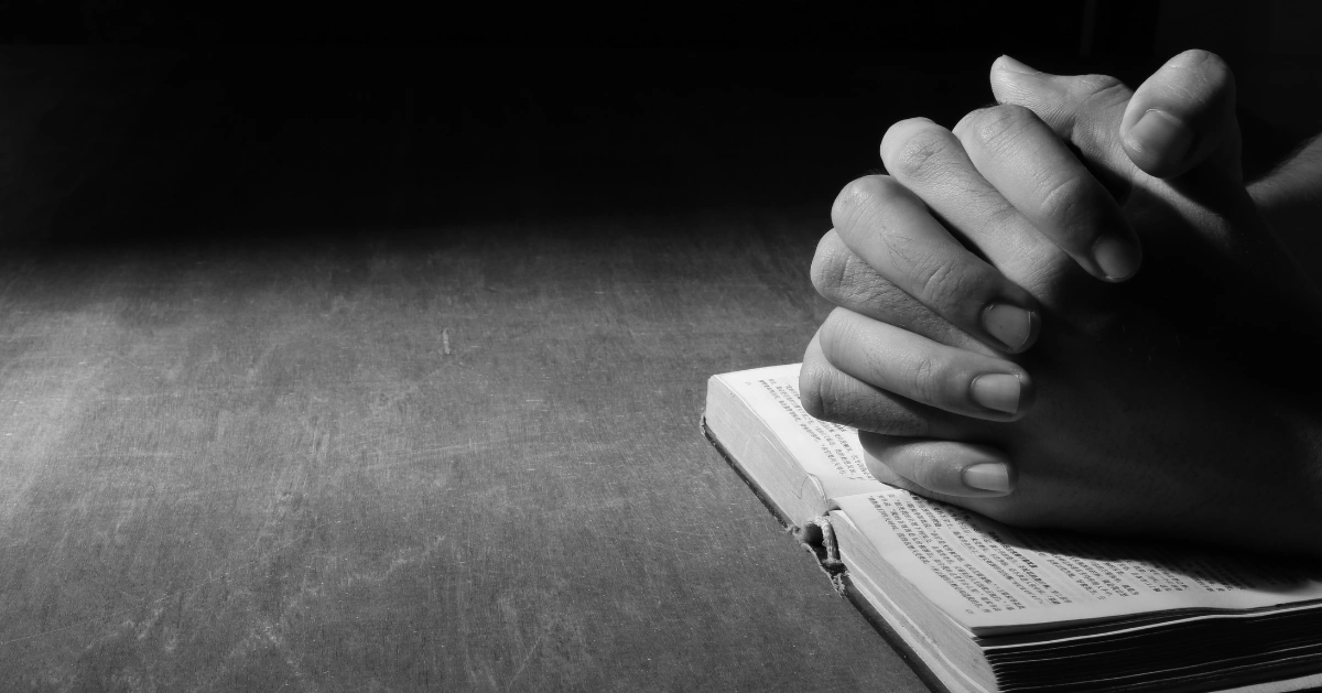 hands praying over a bible