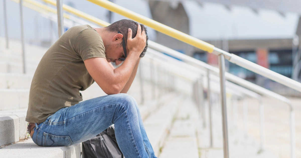 a guy sitting on steps with his head in his hands