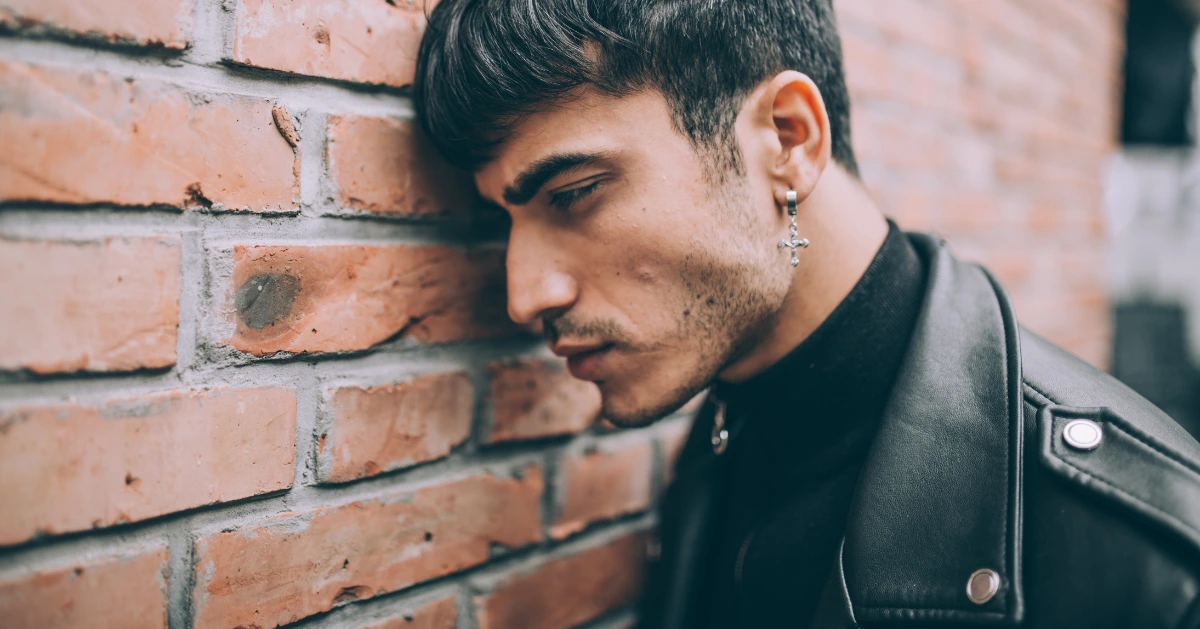 a guy leaning his head on a brick wall