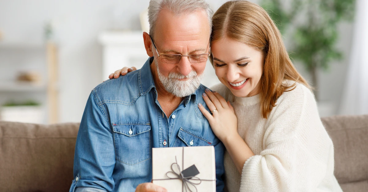 Father and daughter sitting on the couch opening a present