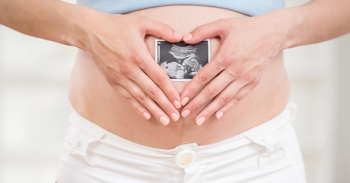 a girl holding a sonogram picture to her belly