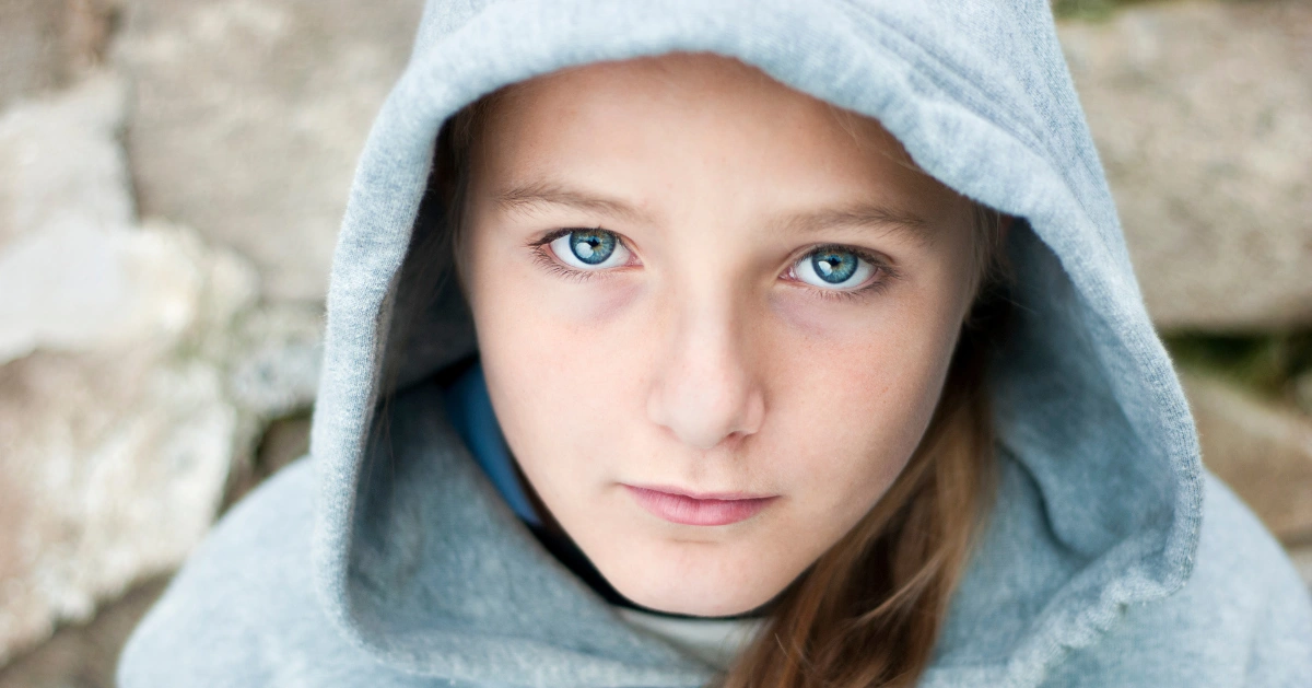 A girl with a blue hoodie looking straight ahead.