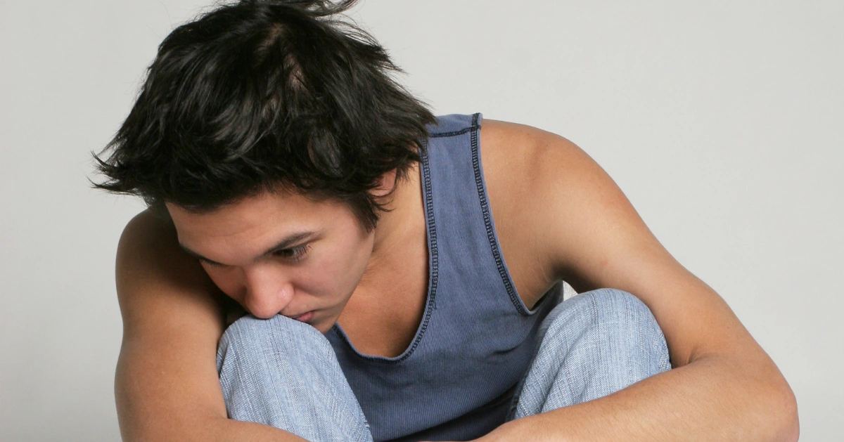 a guy sitting with his chin on his knee