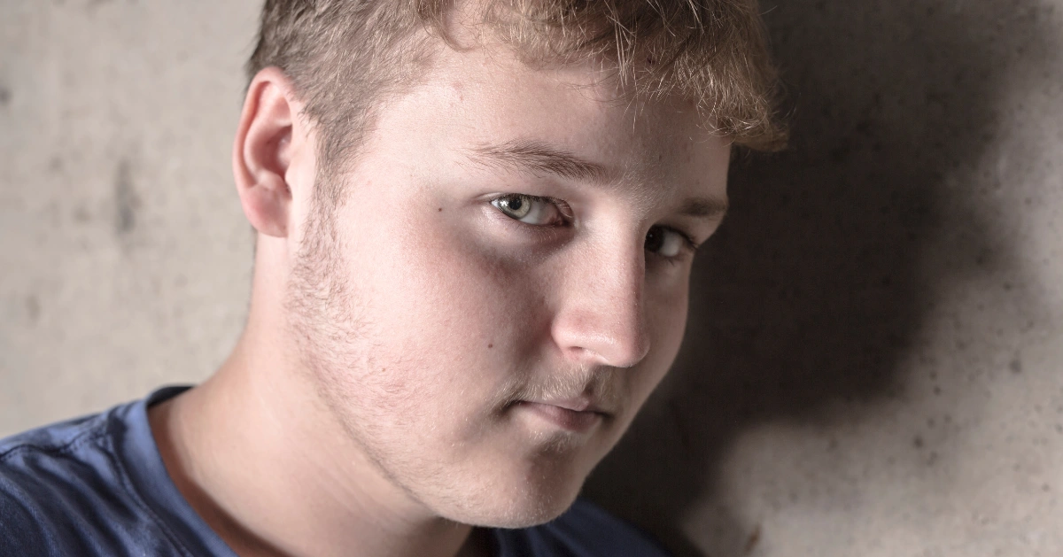 a teen boy looking at the camera sad