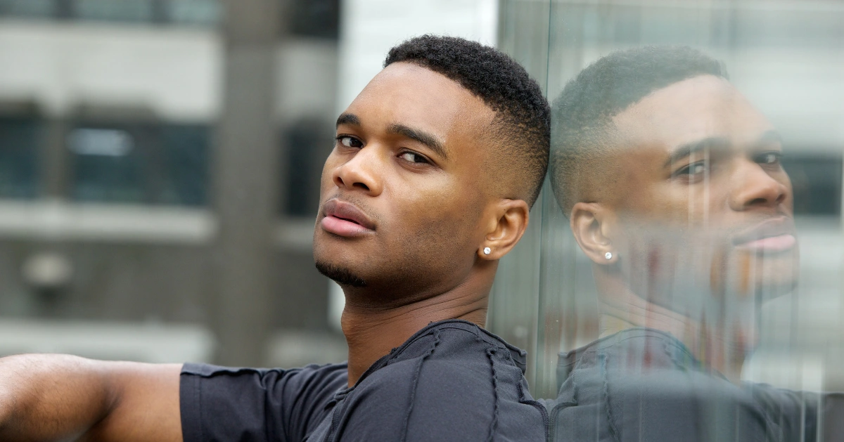 a young man laying against glass with his reflection showing