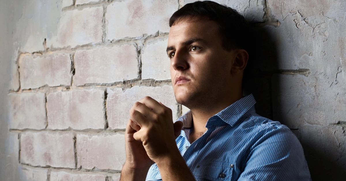 a guy standing against a brick wall