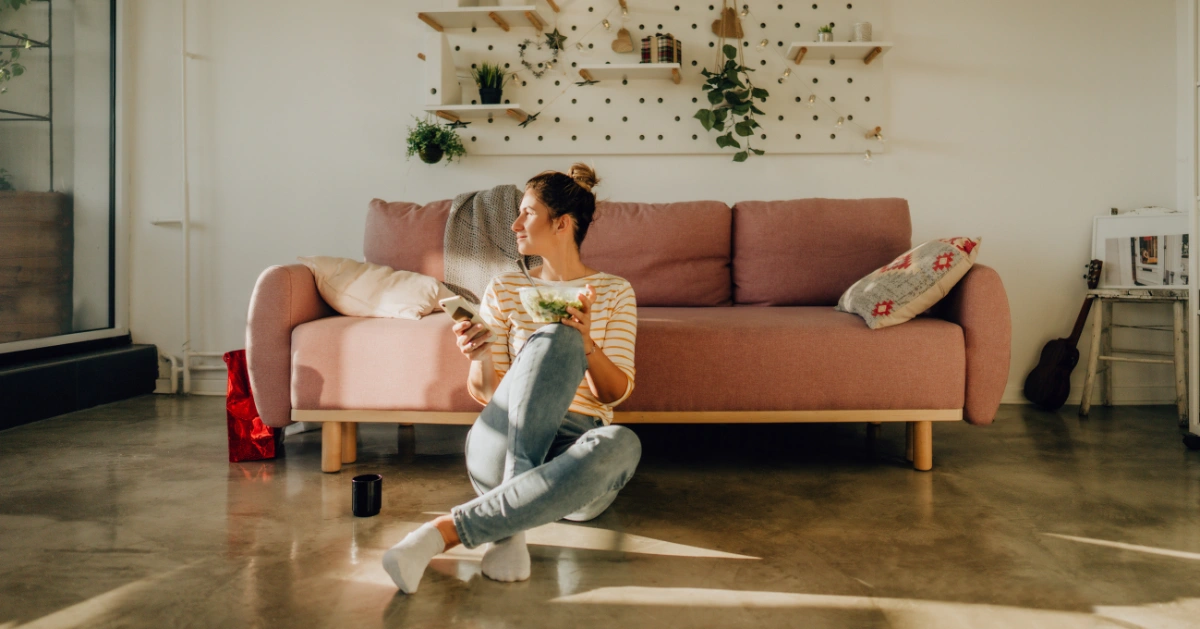 a young lady sitting on the floor in her living room looking out the window