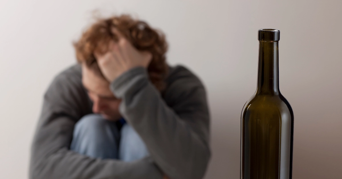 a guy sitting down in front of a bottle