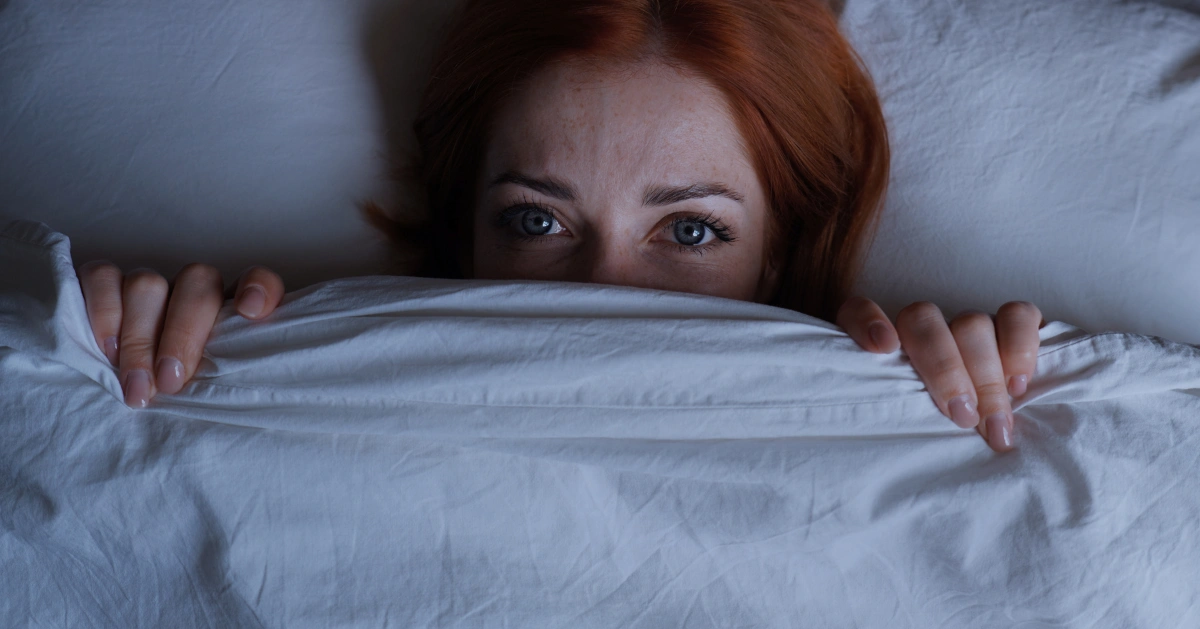 a girl in bed covering half of her face
