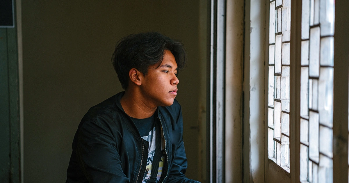 Depressed man looking out a window.