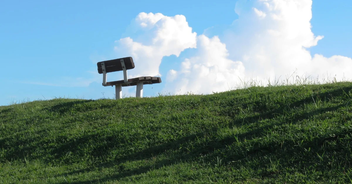 Blue sky and empty bench on a hill